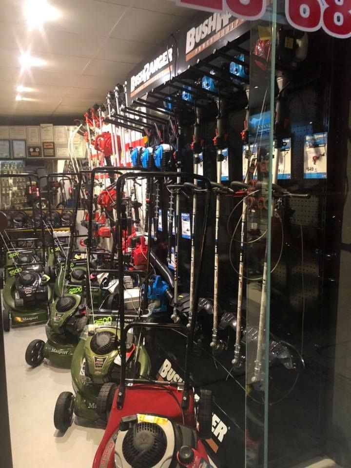 A bunch of lawn mowers are lined up in a store