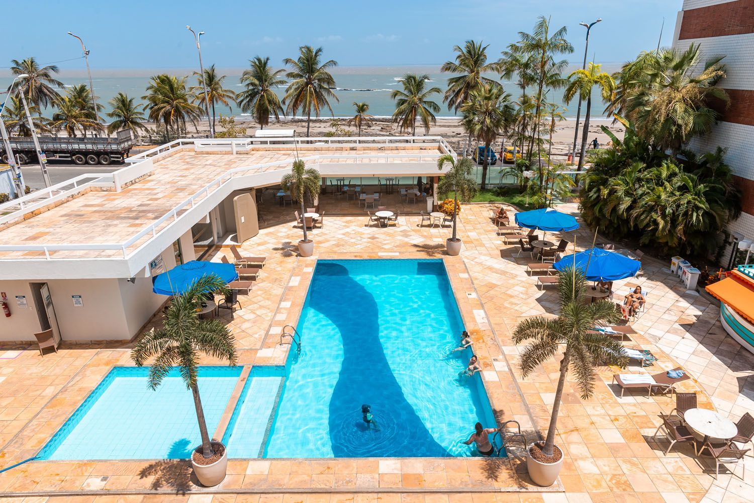 Uma vista aérea de uma grande piscina cercada por palmeiras.