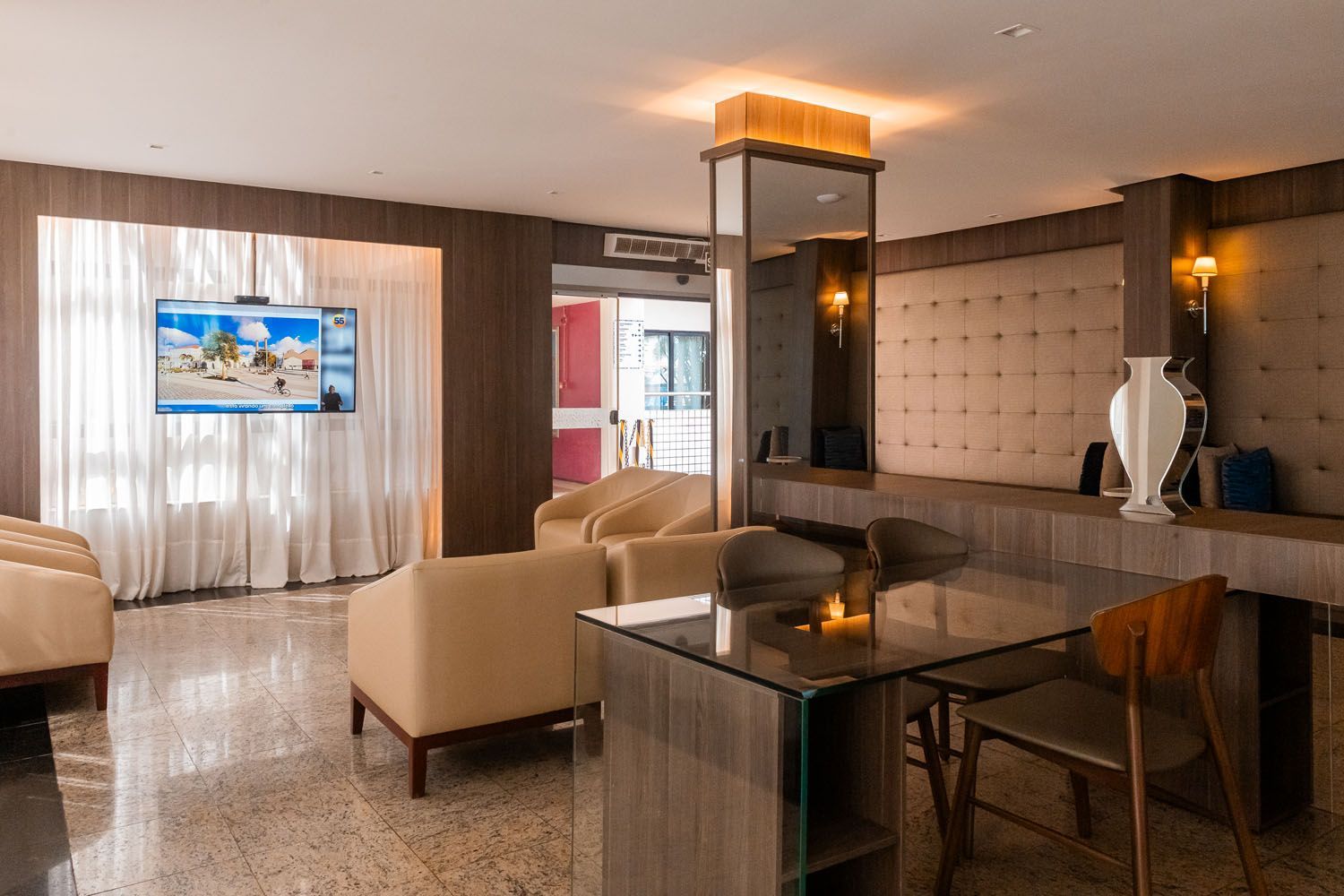 Uma sala de estar com mesa, cadeiras e uma TV de tela plana.