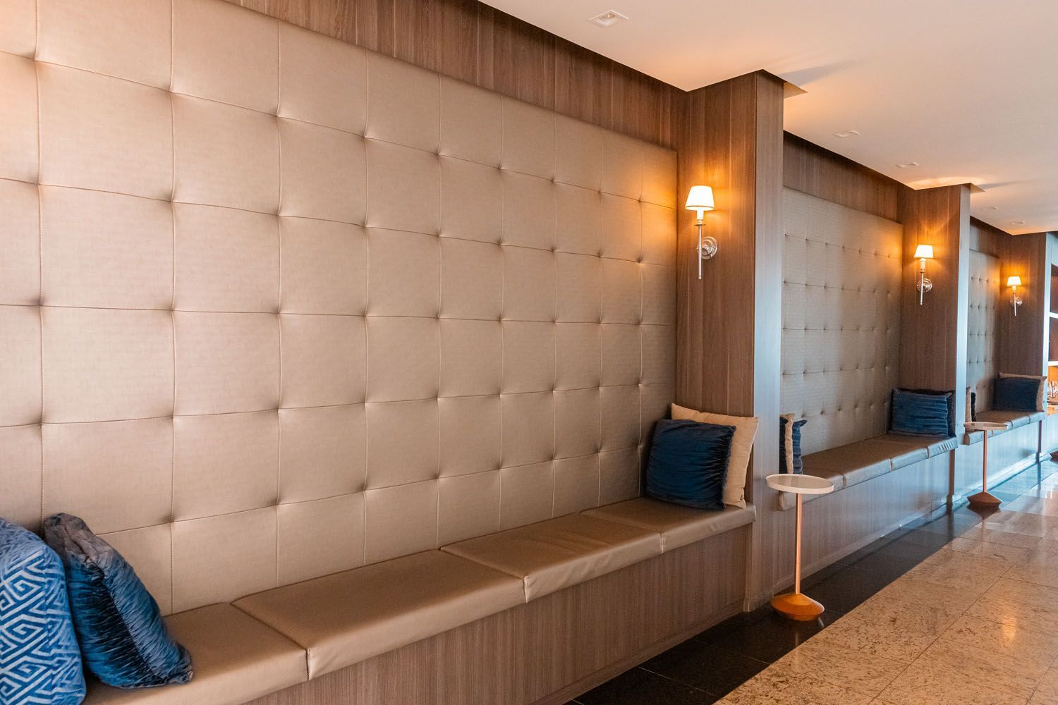 Um corredor com uma fileira de bancos e almofadas na parede.