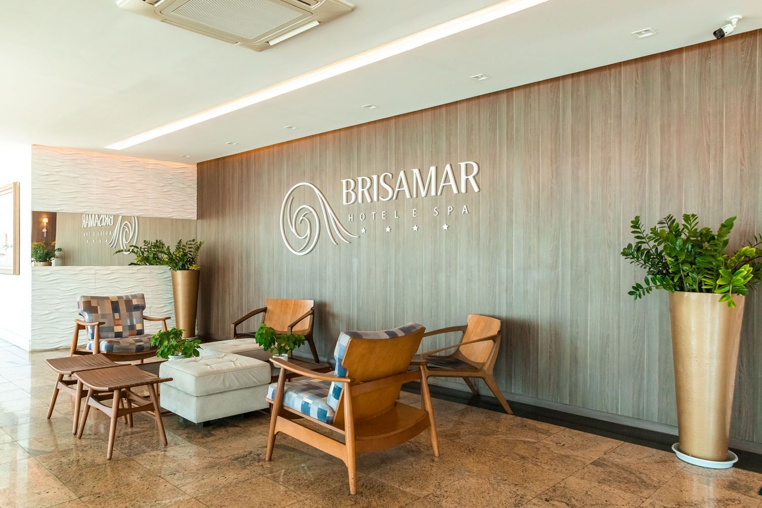 Um lobby de hotel com cadeiras, mesas e plantas.