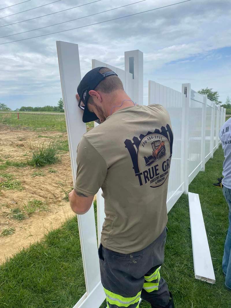 A man is standing next to a white fence.