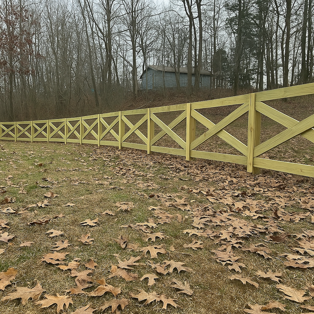 A wooden fence surrounds a grassy field with trees in the background.