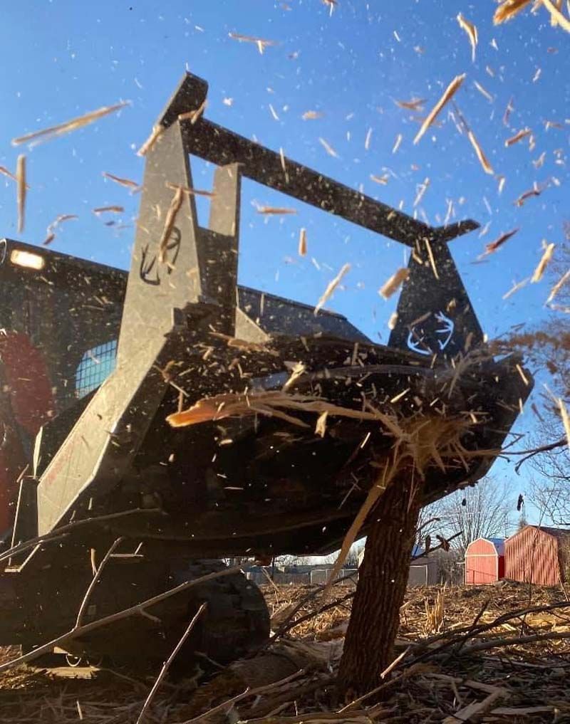 A tractor is cutting down a tree in a field