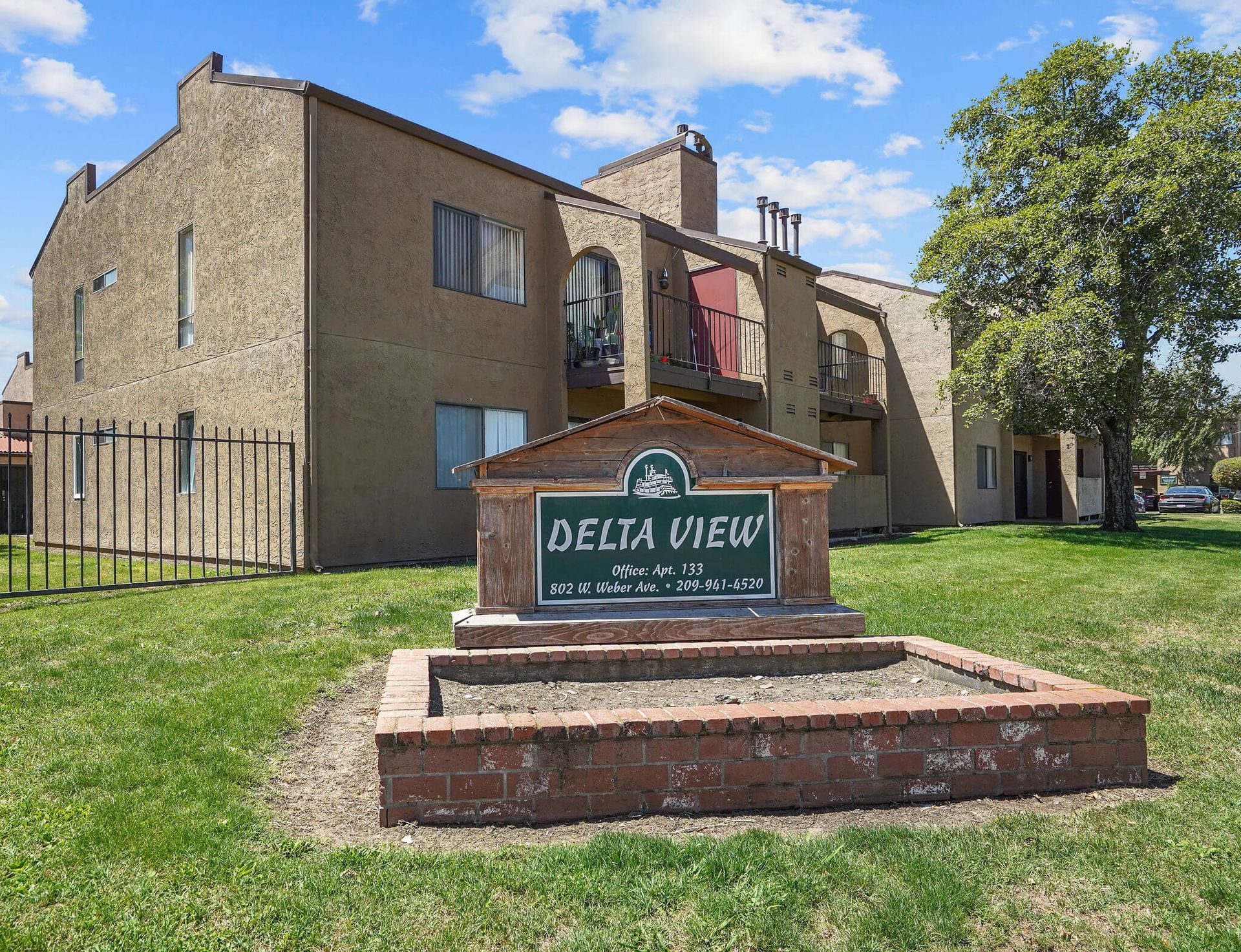 Delta View apartment building sign in front of a tan brick complex on a sunny day