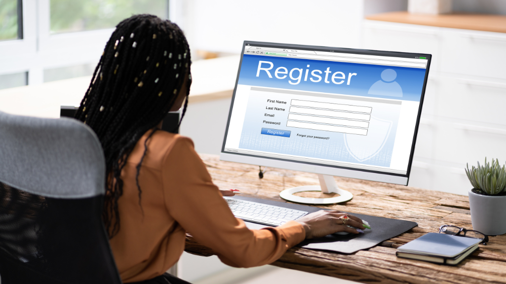 A woman is sitting at a desk using a computer to register. Conference registration. Cvent registration. 