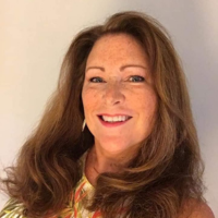 A woman with long brown hair and freckles is smiling for the camera.