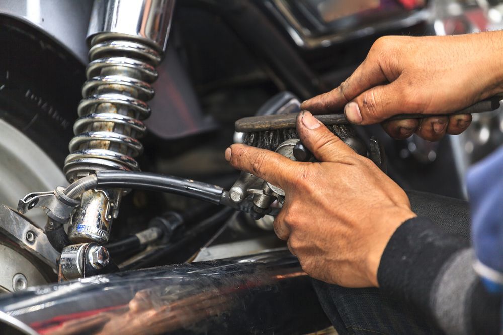 Hands Using Tools to Adjust a Motorcycle Engine in a Garage — Wingham Mechanical in Wingham, NSW