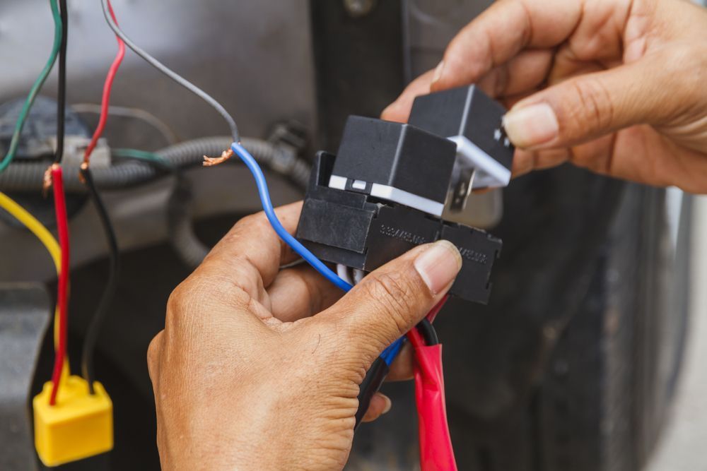 Hands Connecting Wires to a Black Electrical Component in a Workshop Setting — Wingham Mechanical in Wingham, NSW