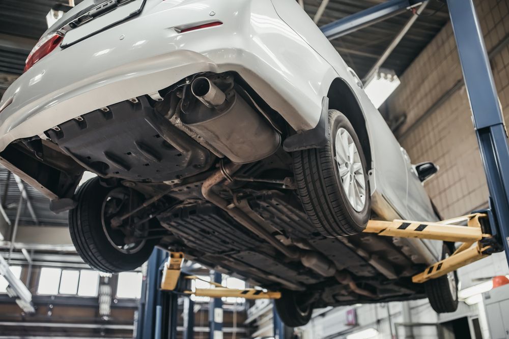 White Car Lifted on a Garage Hoist, Showing the Undercarriage in a Repair Shop — Wingham Mechanical in Wingham, NSW