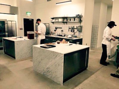 Two chefs are working in a kitchen with marble counter tops