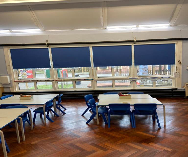 A living room with a desk and chairs and a lot of windows.