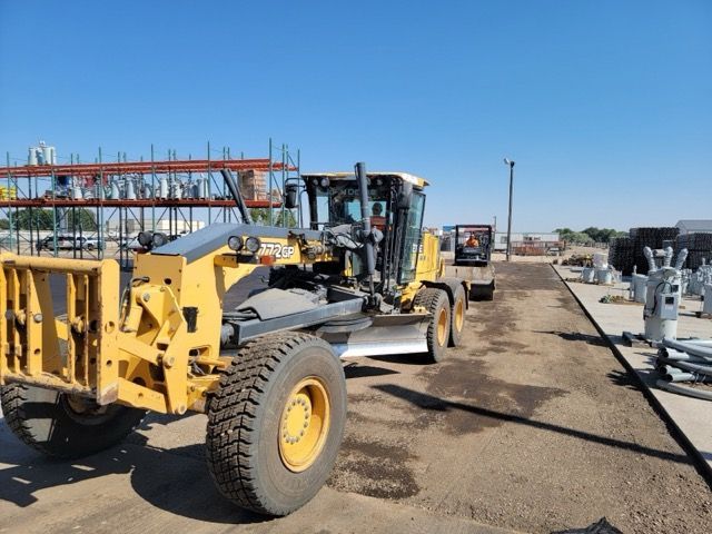 Two people near a white work truck with side storage. One in orange, one in brown, both near open doors. Cloudy sky.
