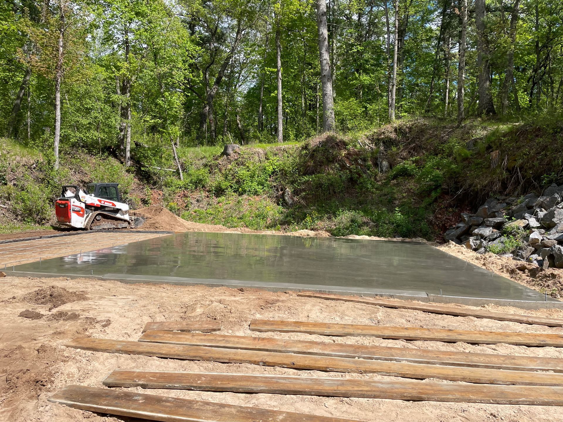 A freshly poured concrete driveway in front of suburban houses with green lawns.