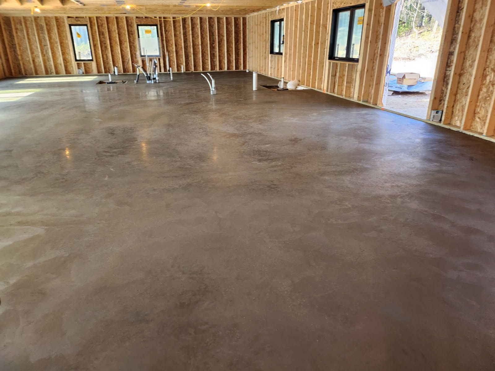 Construction workers pour wet concrete from a truck into a wooden frame at a job site as one person reviews documents.