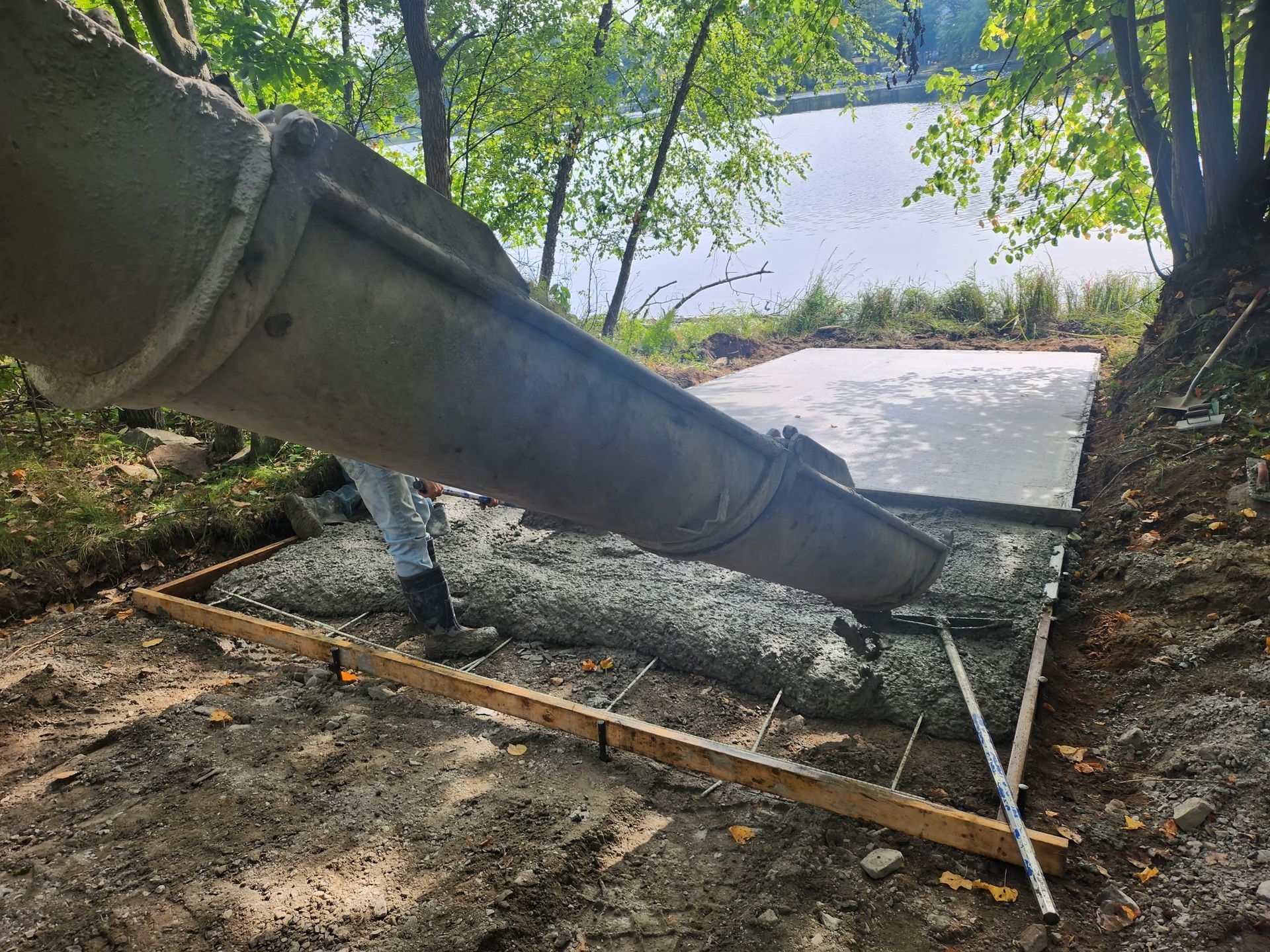 A close-up view of a grey concrete foundation wall at a construction site, featuring metal anchor bolts along the edge.