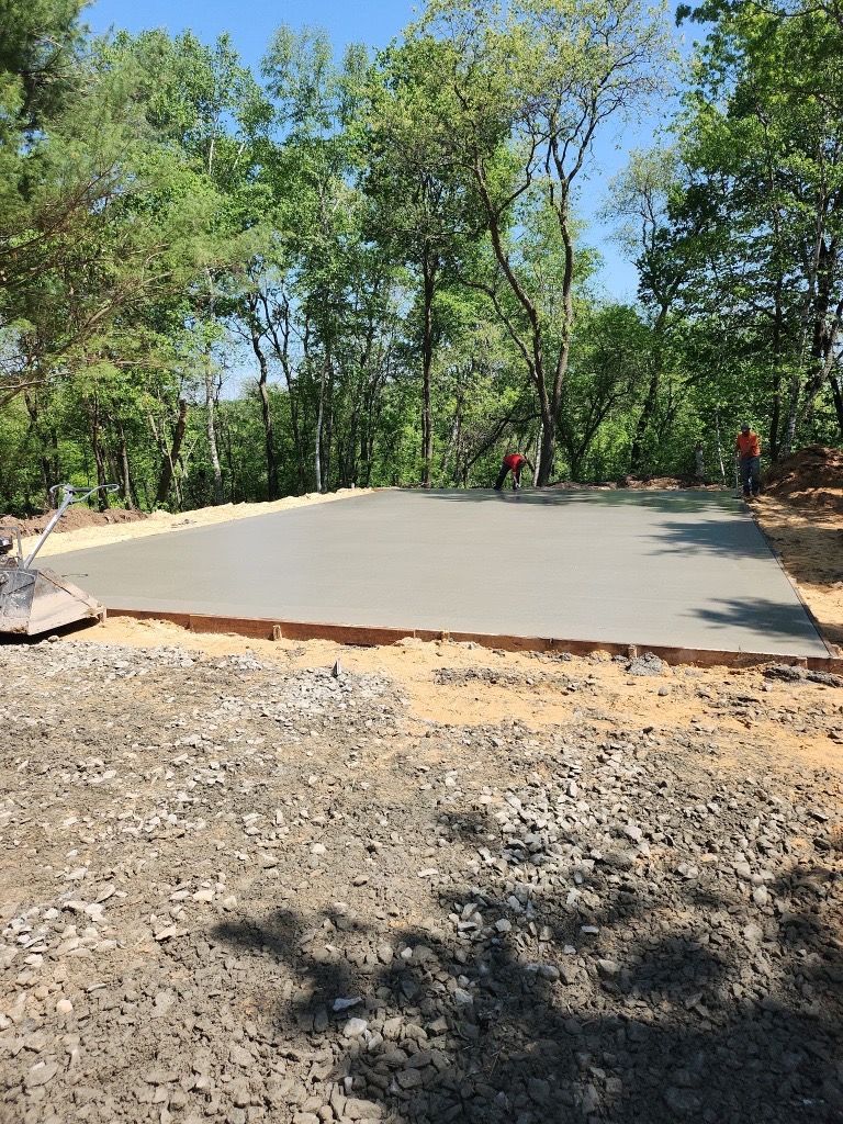 A freshly poured concrete driveway in a suburban neighborhood with houses and grass on either side.