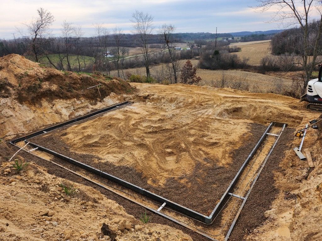 A yellow bulldozer and orange excavator work on a dirt plot in front of suburban houses.