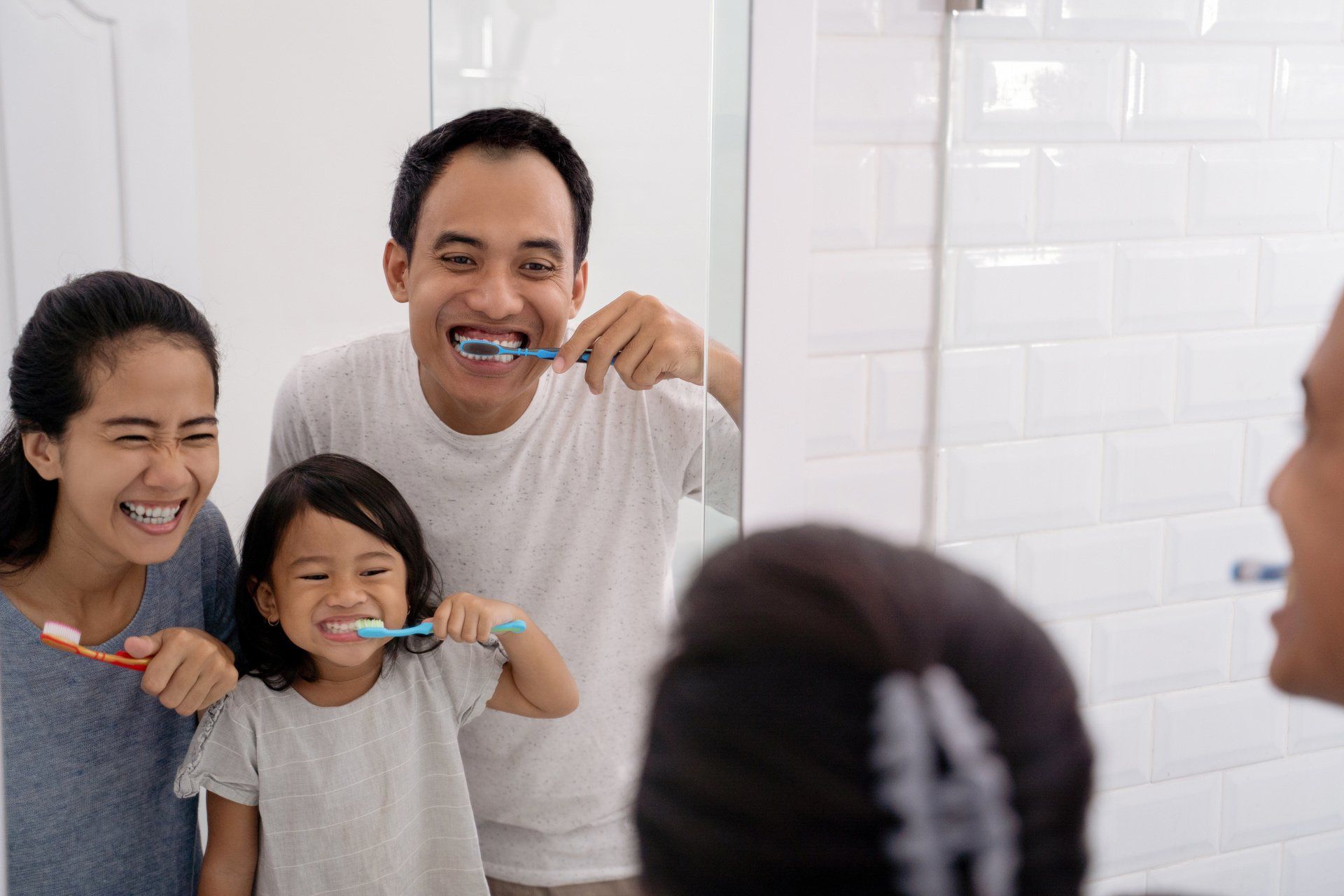 Parent with daughter brushing teeth in the bathroom
