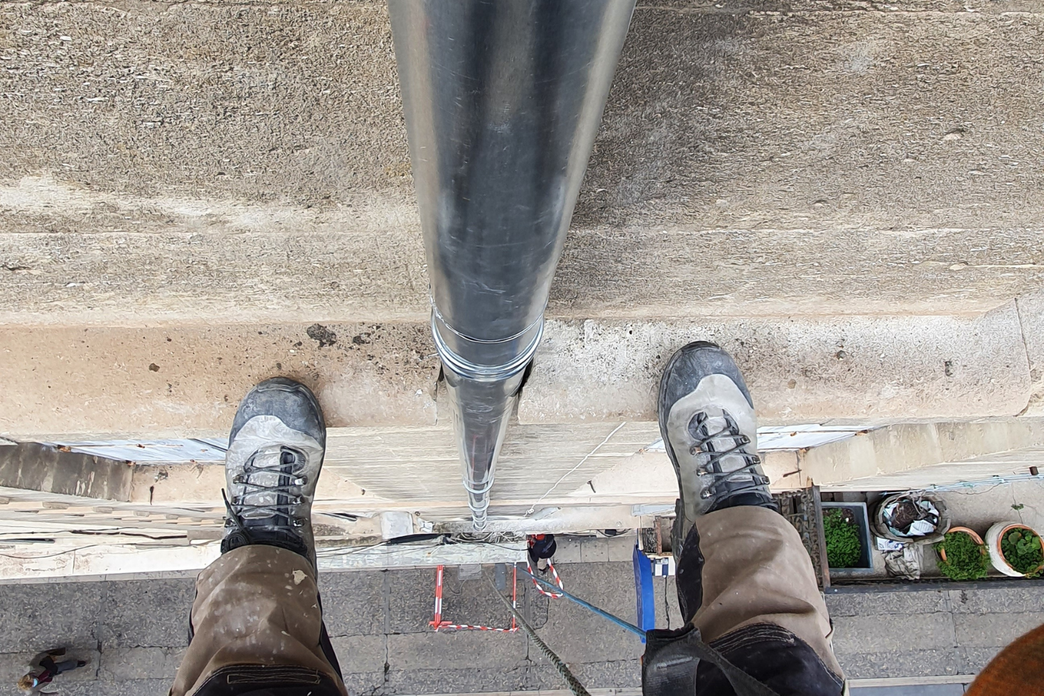 Une personne se tient à côté d'un tuyau sur un trottoir.