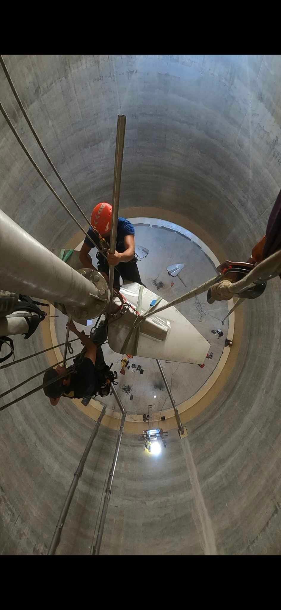 Un groupe de personnes travaille sur un gros tuyau dans un tunnel.