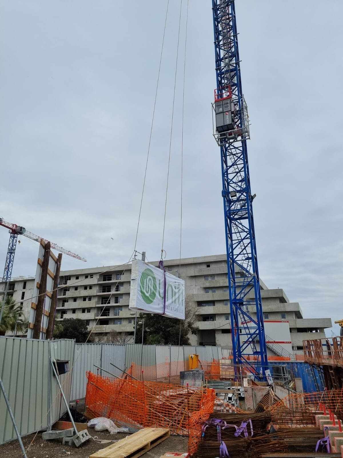 Un chantier de construction avec une grue et un bâtiment en arrière-plan.