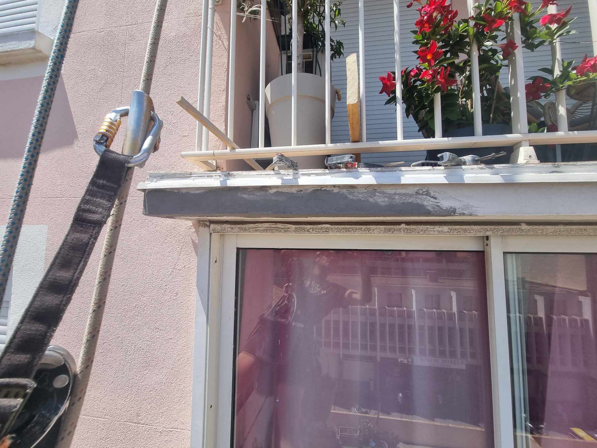Un balcon avec des fleurs et une corde qui y pend