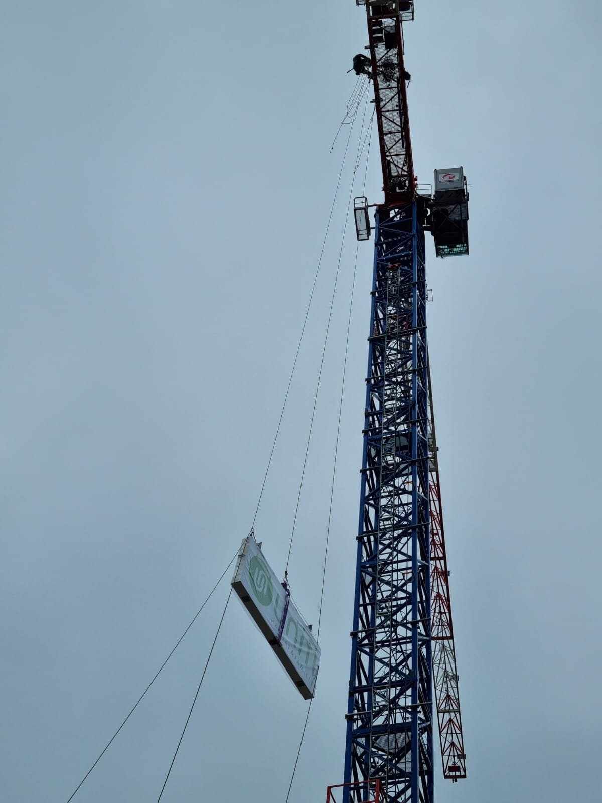 Une grue soulève un morceau de béton dans les airs.