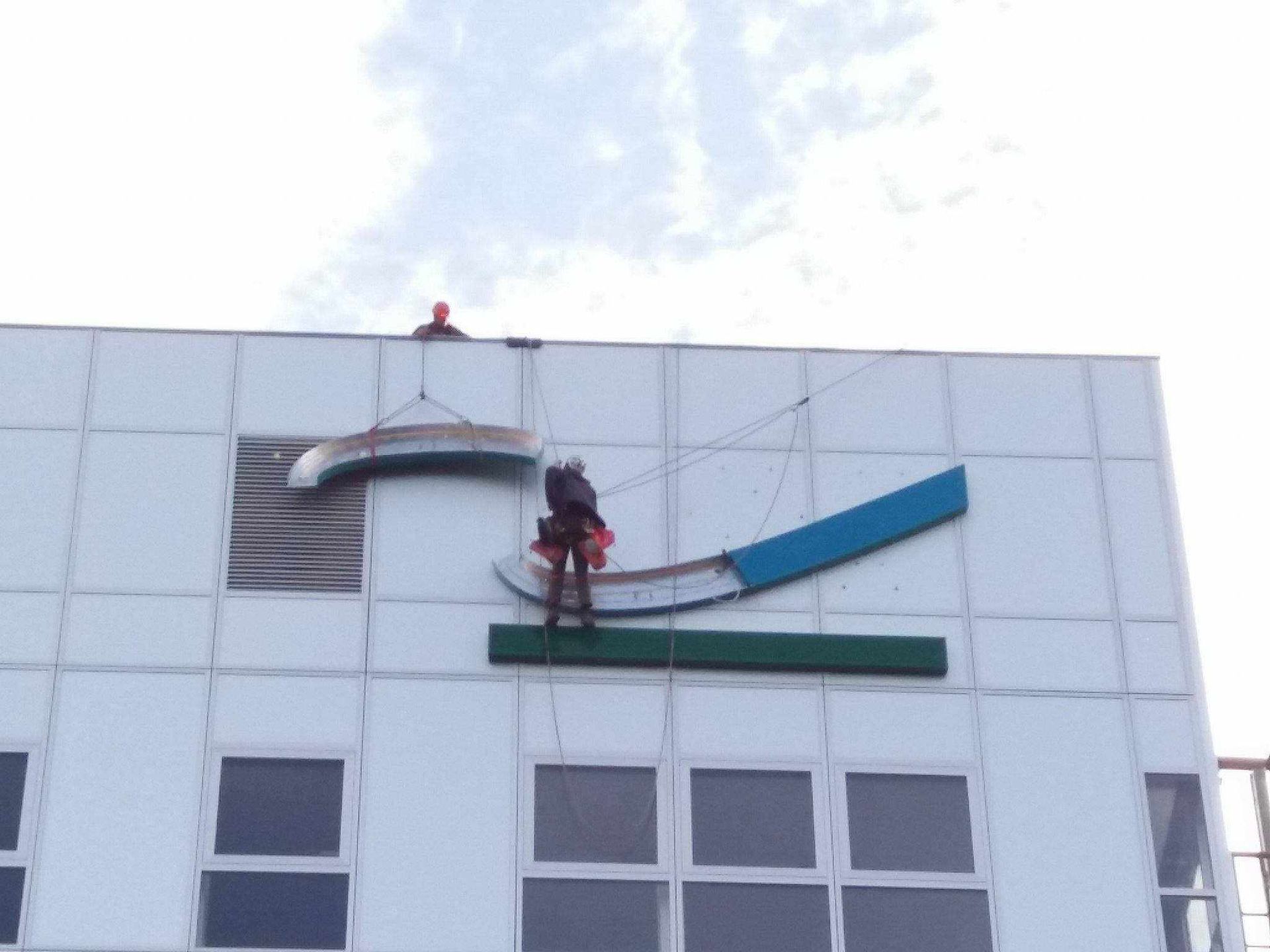 Un homme travaille sur le côté d'un bâtiment