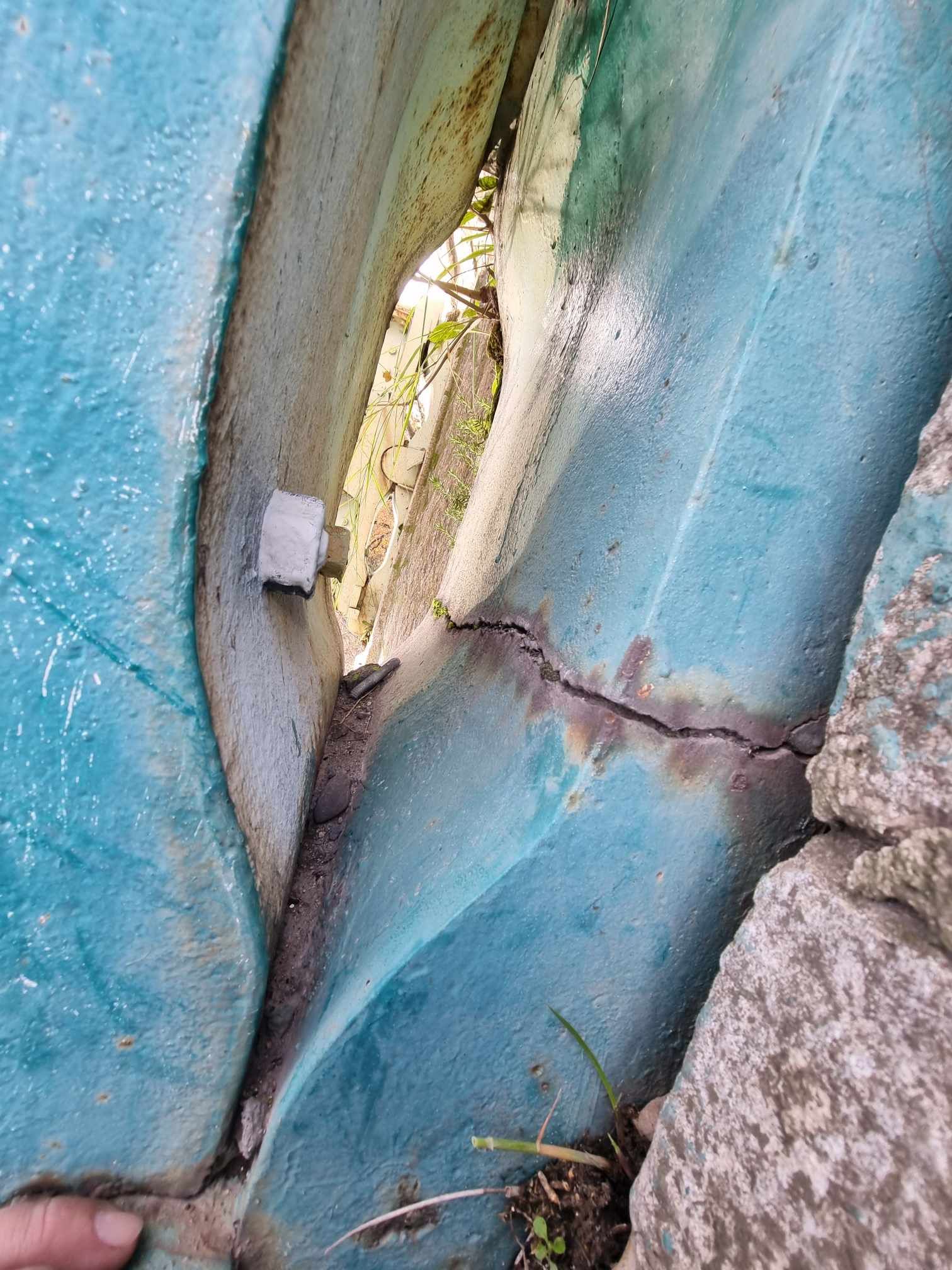 Une personne tient un morceau de plastique bleu entre deux rochers.