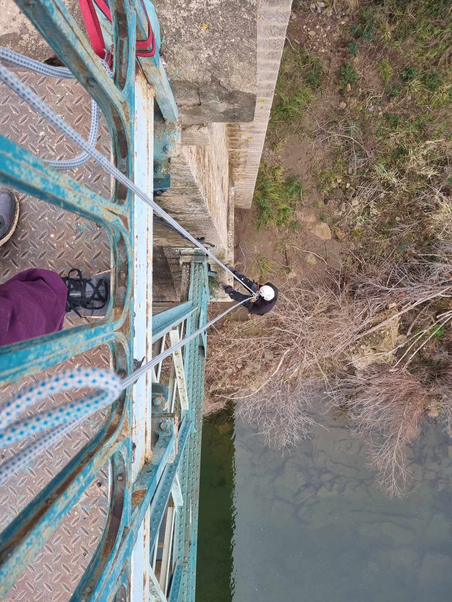 Une personne escalade un pont au-dessus d'un plan d'eau.