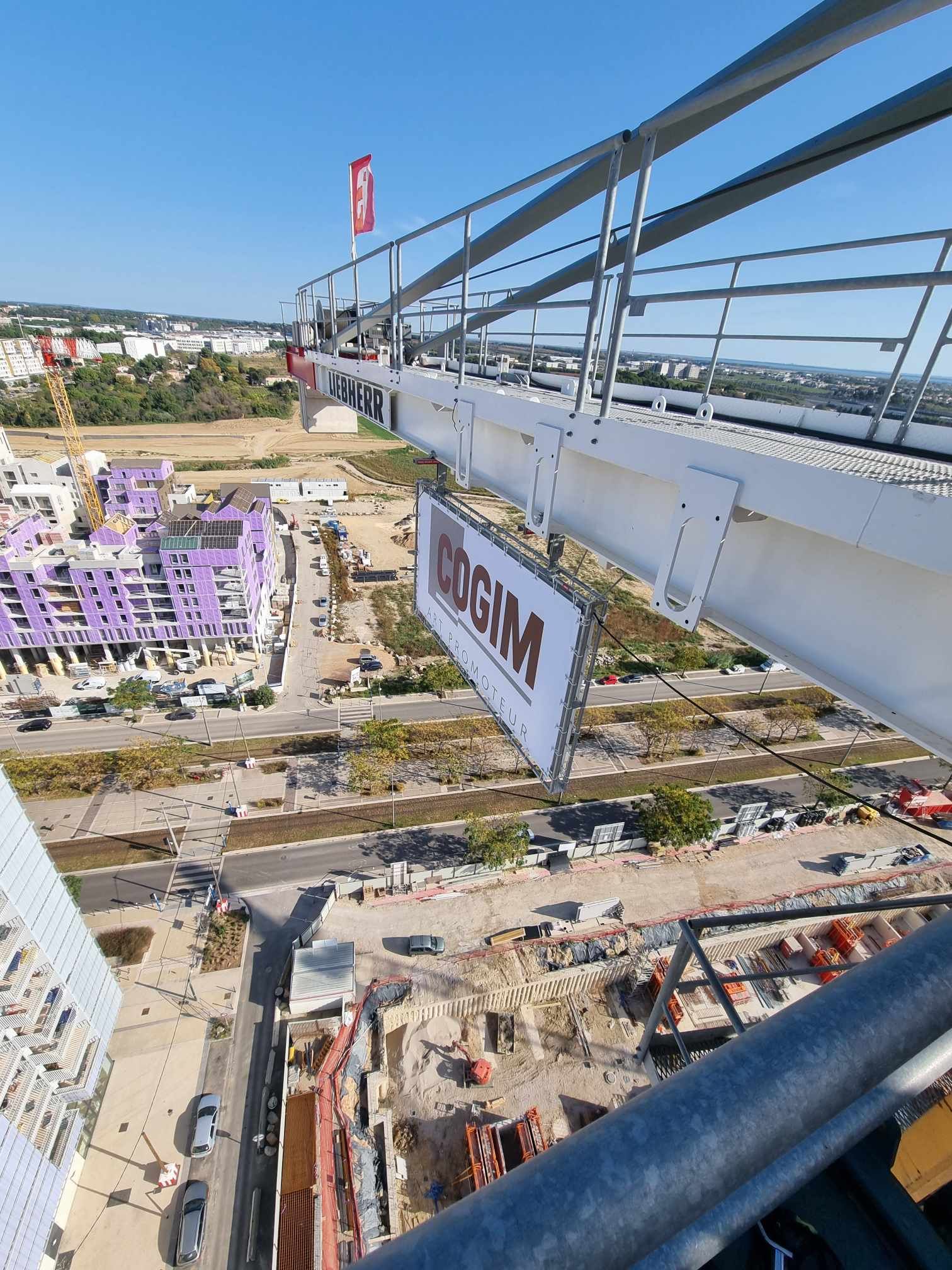 Une vue aérienne d'un chantier de construction avec un panneau suspendu à une grue.