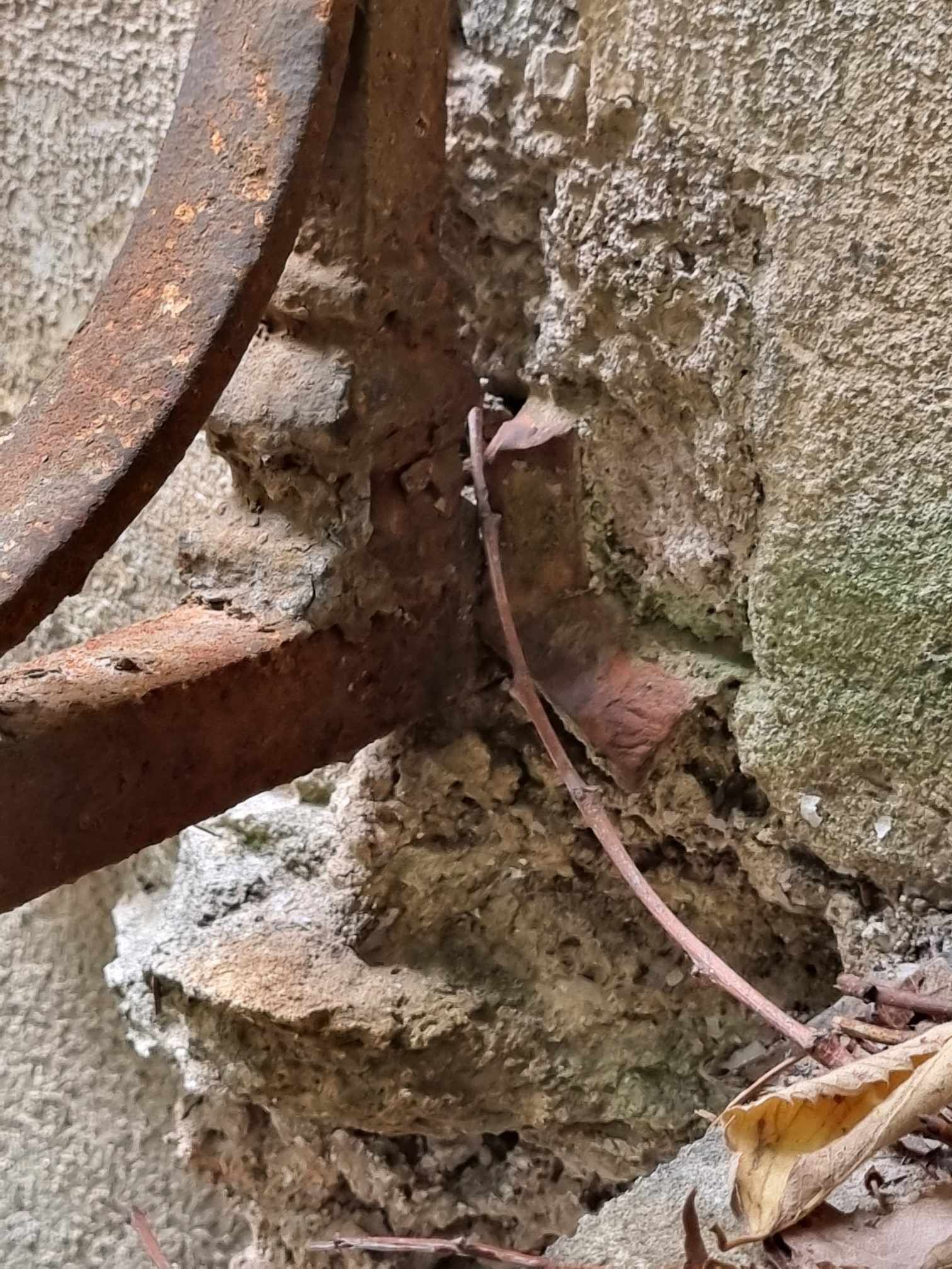 Un objet en métal rouillé est posé à côté d'un mur de pierre.