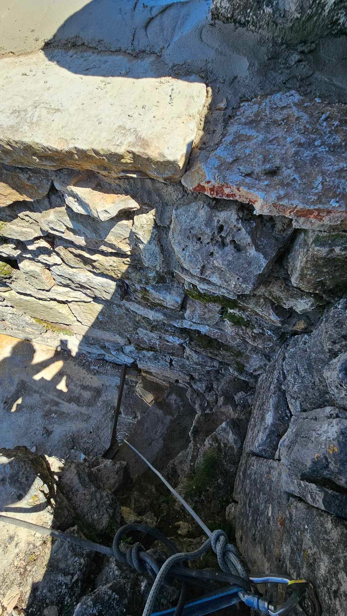 Une personne escalade un mur rocheux avec une corde.