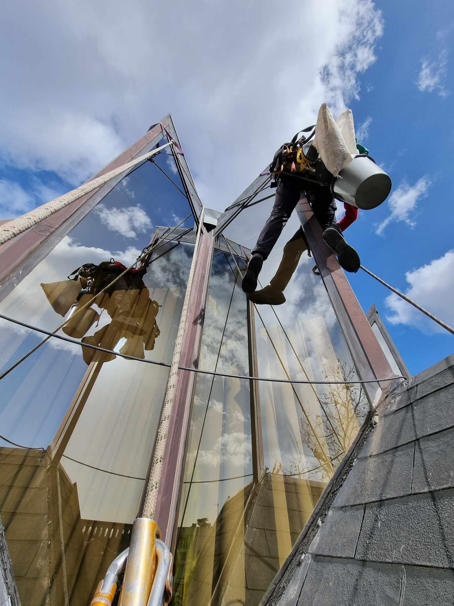 Un homme est debout sur un toit et nettoie les fenêtres d'un bâtiment.