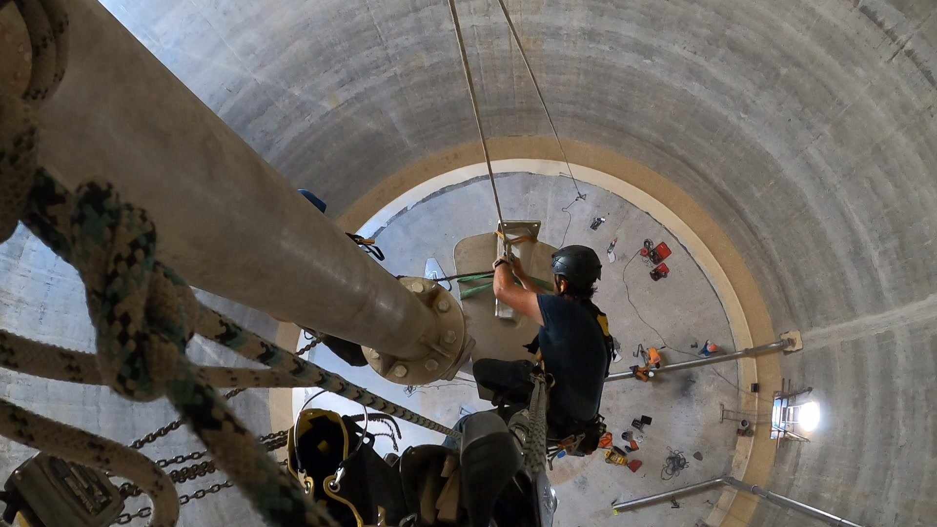 Un homme travaille sur un tuyau dans un cylindre en béton.