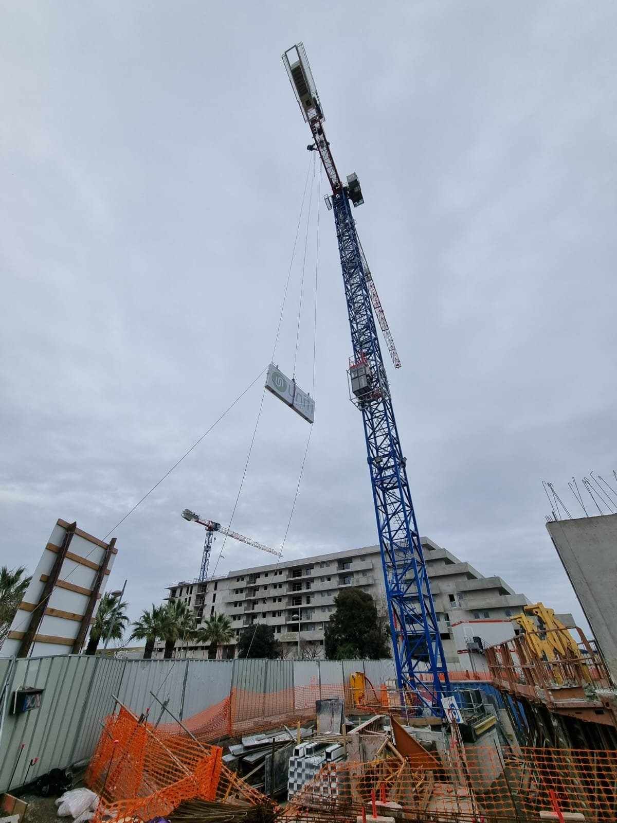 Une grande grue soulève un morceau de métal sur un chantier de construction.