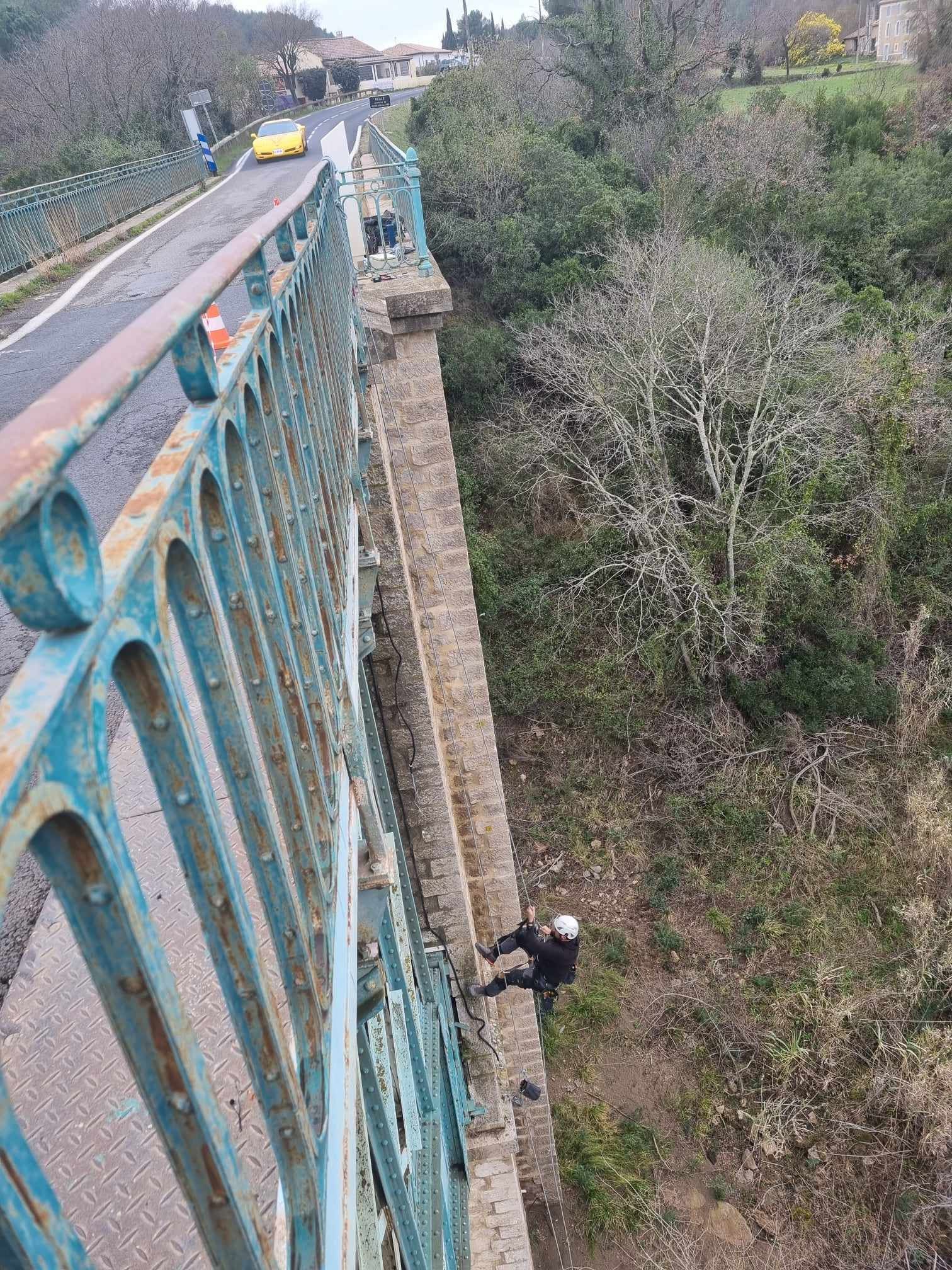 Un homme grimpe sur le côté d'un pont.