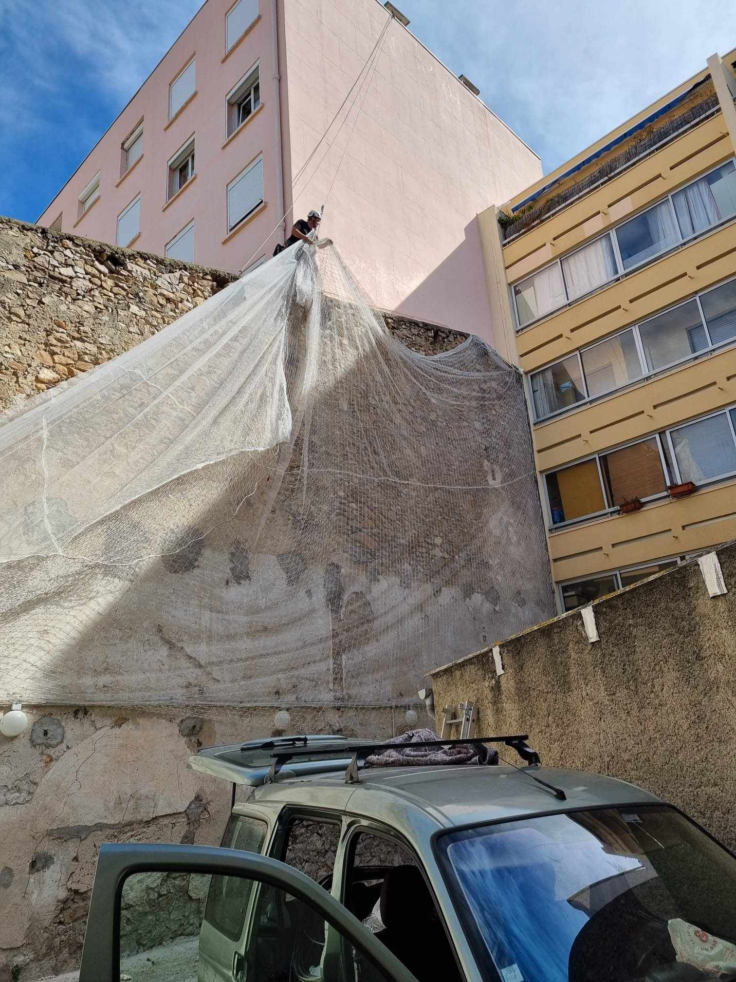 Une voiture est garée devant un bâtiment avec une bâche dessus.