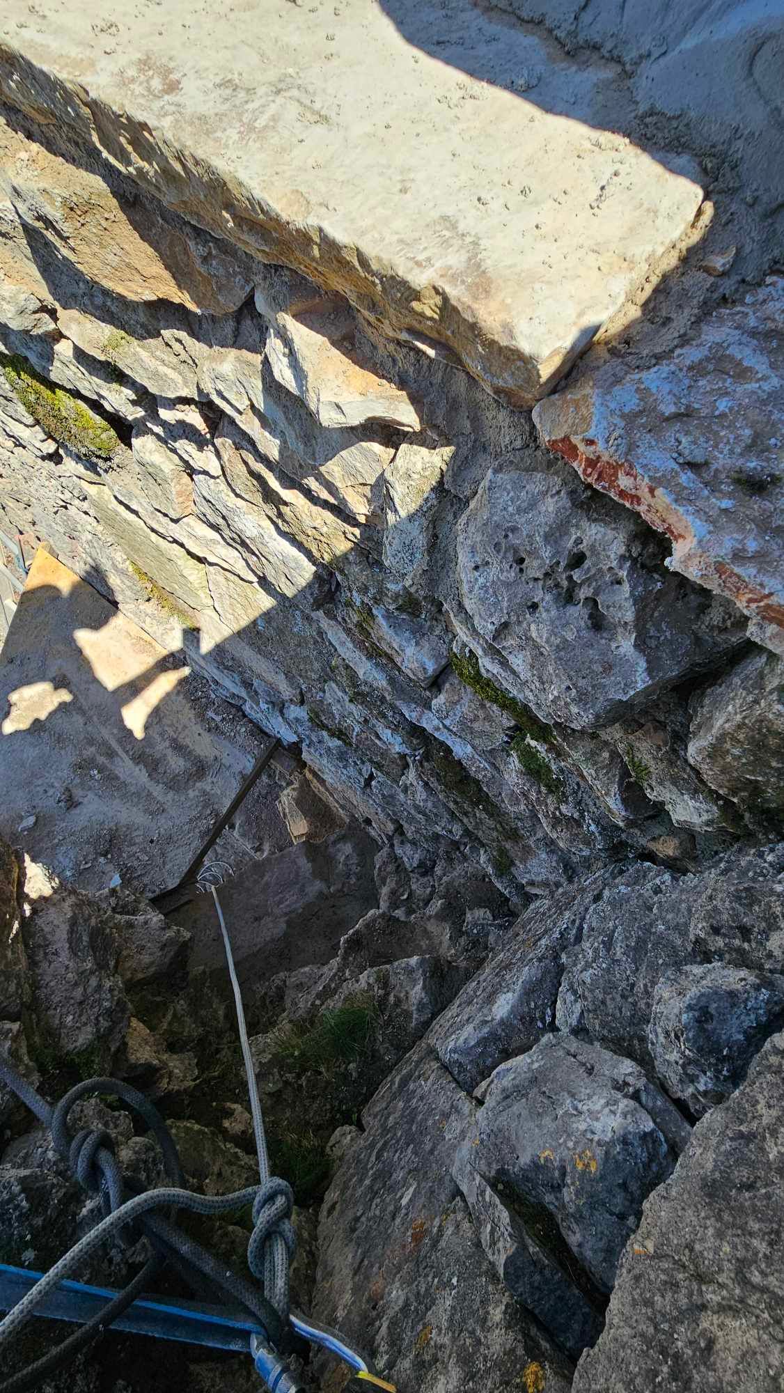 Un gros plan d'un mur de pierre avec une corde qui y pend.