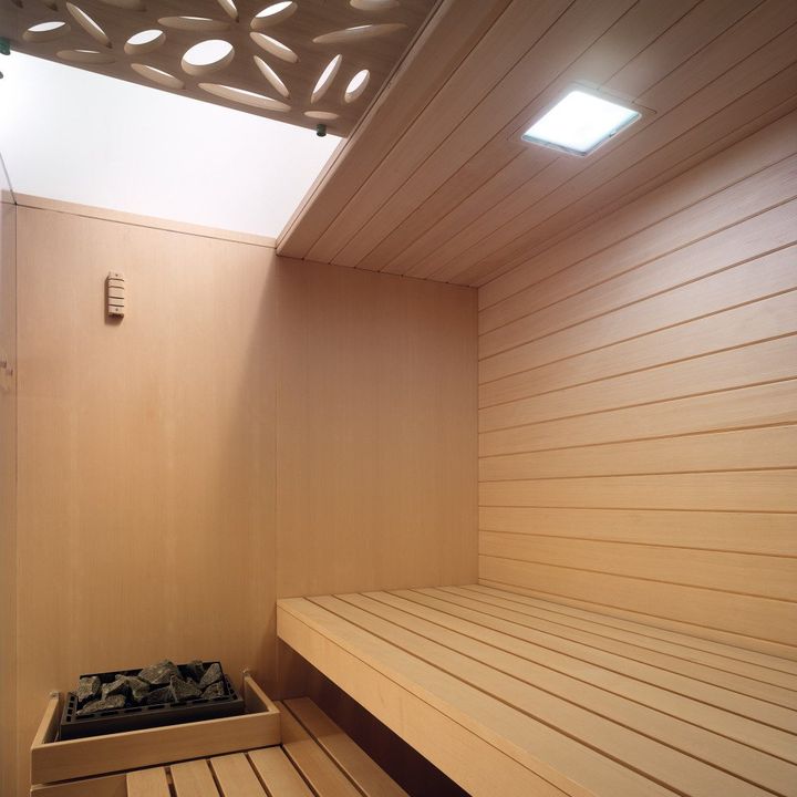 sauna moderna in legno chiaro con pietre laviche