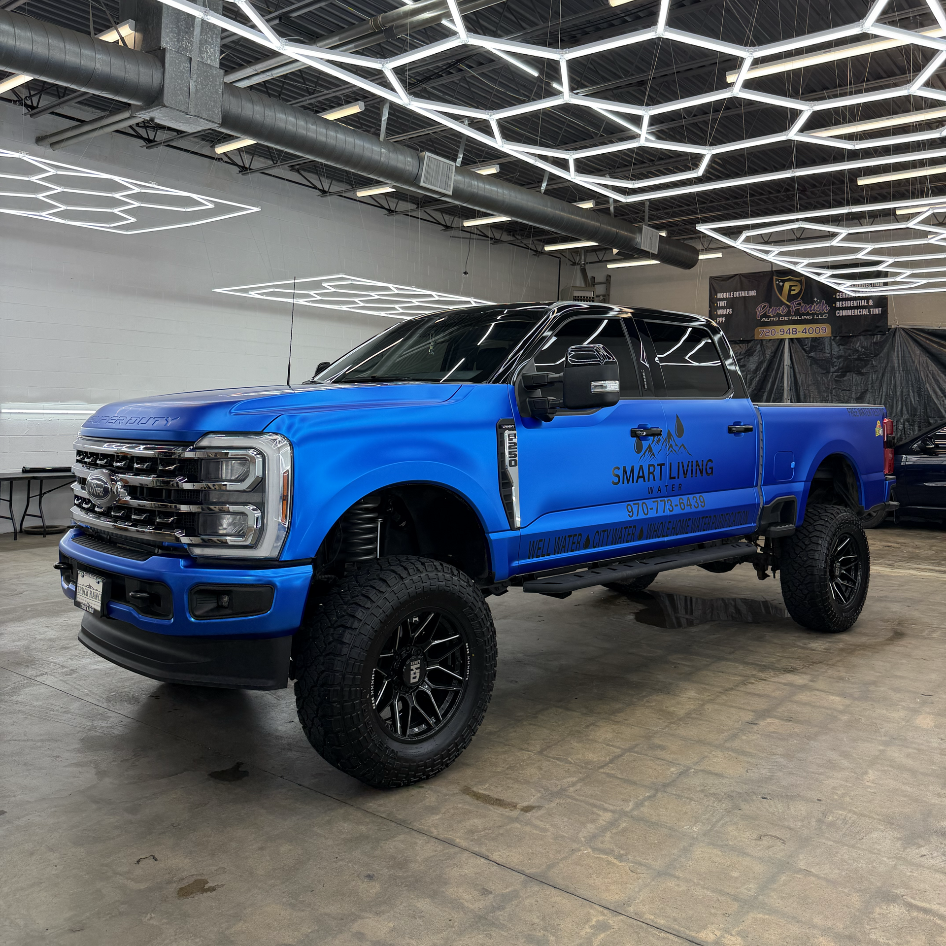Bright blue lifted pickup truck displayed indoors under geometric ceiling lights