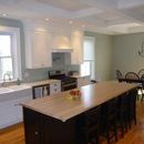 A spacious kitchen with white cabinets, a large island with a light wood countertop, and sage green walls.