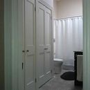 A view of a bathroom doorway featuring white double doors, with a toilet, shower curtain, and vanity visible inside.