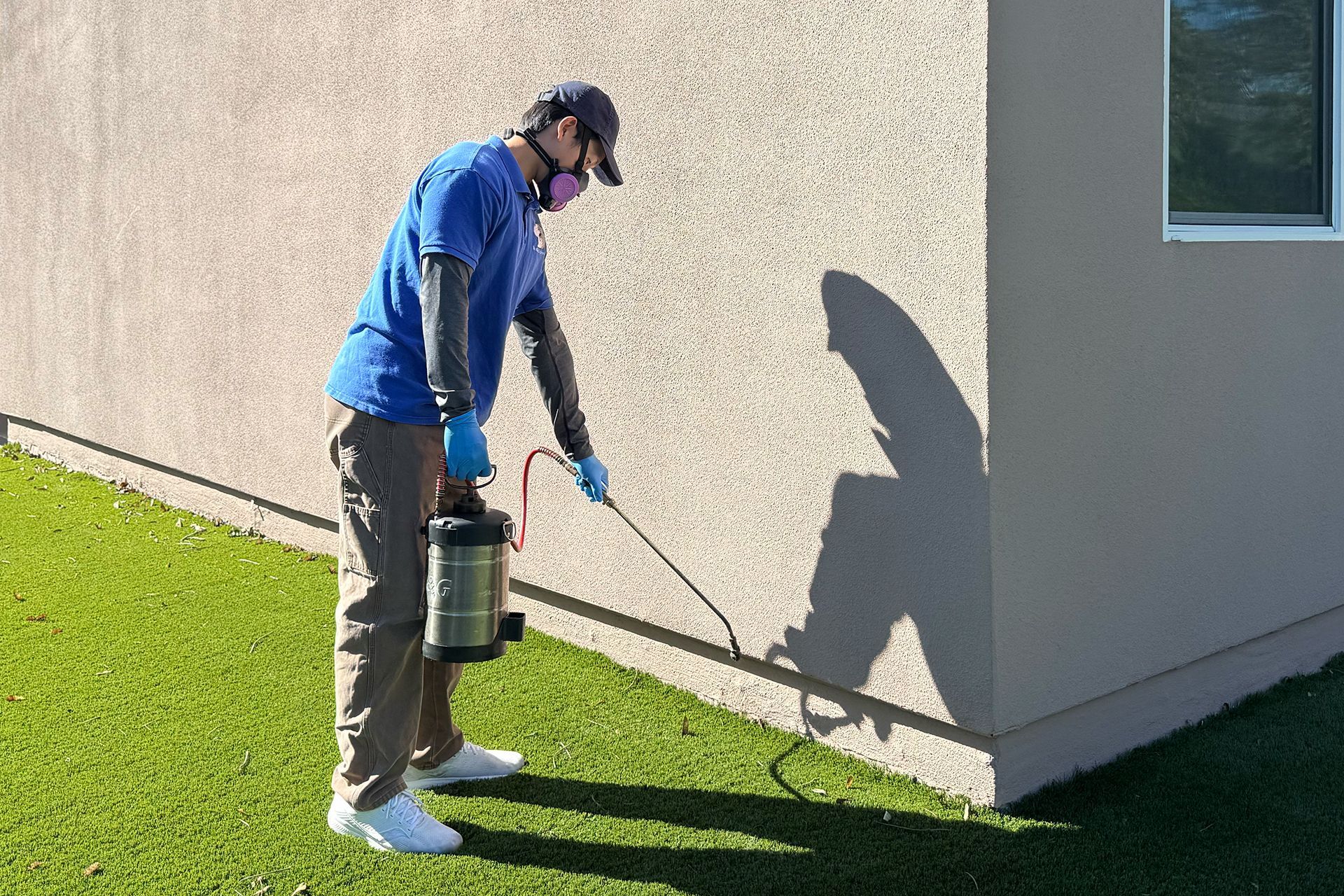 A man in a protective suit is spraying a kitchen with a sprayer.