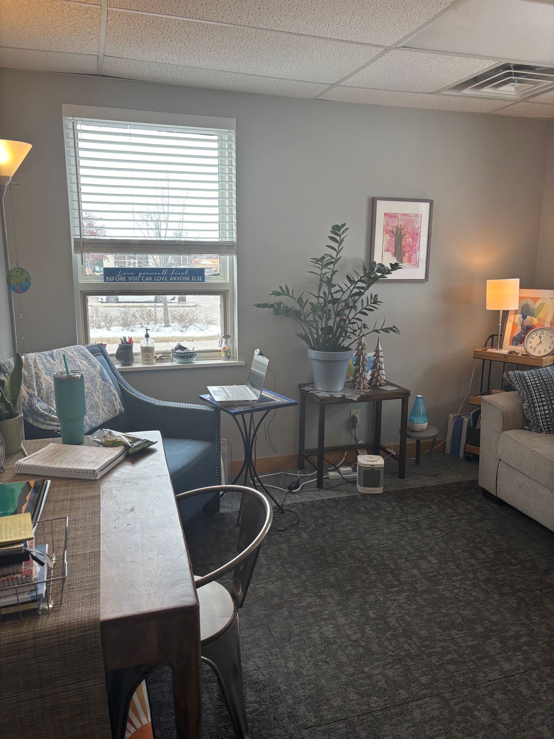 A living room with a couch , desk , chair and window.