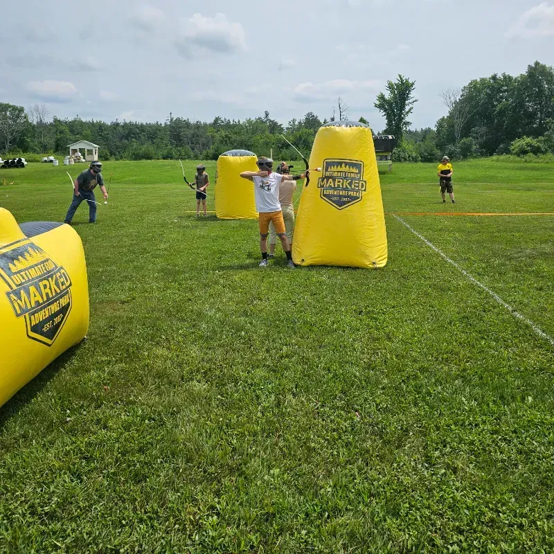 A group of people are playing a game of archery in a field