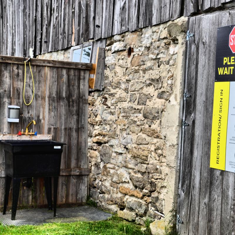 A sign in front of a stone wall says please wait