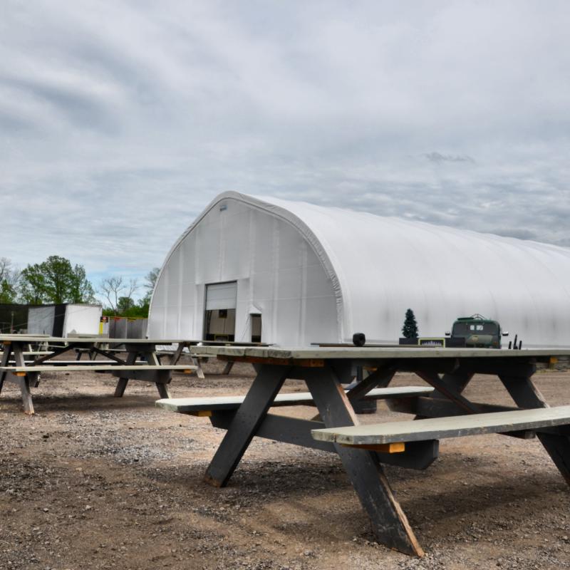 A row of picnic tables in front of a large white building