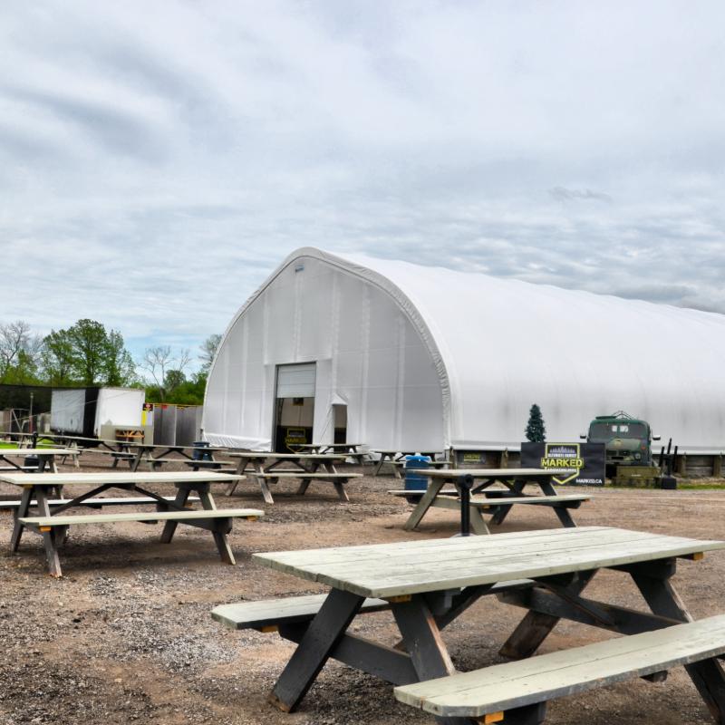 A bunch of picnic tables in front of a large white building